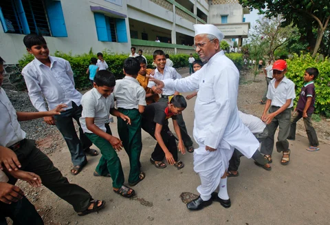 Students touch the feet of Anna Hazare as a sign of respect as he visits one of his schools in the Ralegan Siddhi. (Photo: Reuters)