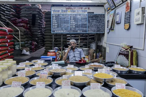 A vendor talks on the phone as rice samples sit on display at a warehouse store in the Vashi Agricultural Produce Market Committee (APMC) wholesale market in Mumbai, India. (Photographer: Dhiraj Singh/Bloomberg)