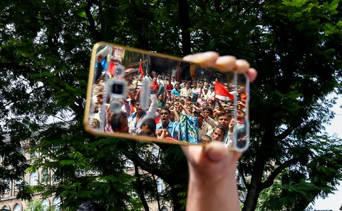 People reflected on a phone as they attend a protest against what attacks on the dalit community in Mumbai, 12 August 2016. (Photo: Reuters)