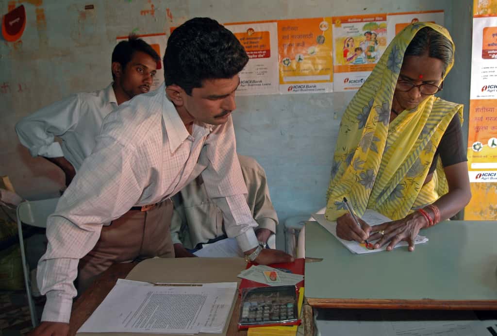 A female who owns five acres of land, signs at a rural office of ICICI Bank in Chincholi, India (Photographer: Santosh Verma/Bloomberg News)