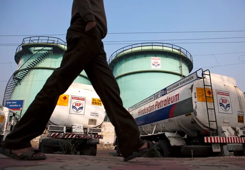 A man walks past petrol tankers, outside an oil depot in New Delhi, India. (Photographer: Prashanth Vishwanathan/Bloomberg)