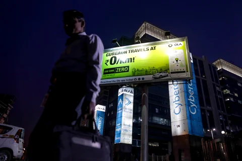 A pedestrian walks past an advertisement for the Ola ride-hailing service and application, owned by ANI Technologies. (Photographer: Dhiraj Singh/Bloomberg)