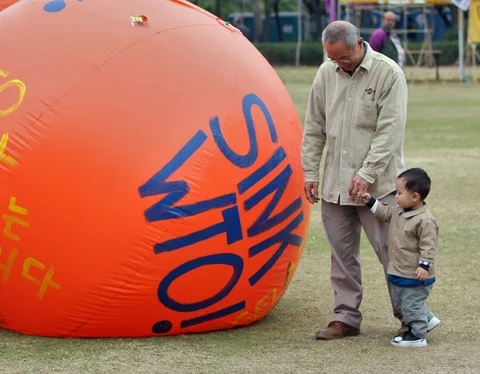 Hong Kong residents walk past balloons which are part of protests against the World Trade Organization’s Sixth Ministerial Conference in a park in Hong Kong, China on December 14, 2005. (Photographer: Lucas Schifres/Bloomberg News)