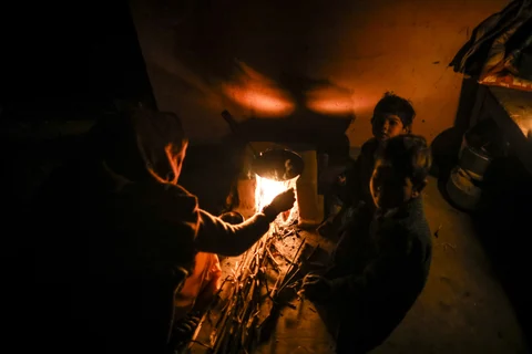 A woman cooks on a stove in the light provided by a kerosene lamp in her home at night in the village of Fateh Nagla, Uttar Pradesh, India, on January 14, 2017. (Photographer: Prashanth Vishwanathan/Bloomberg)