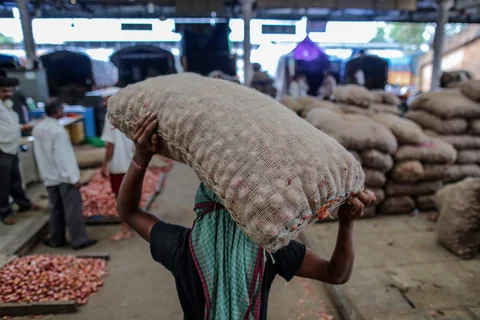 A worker carries a sack of onions on his head at the Vashi Agricultural Produce Market Committee (APMC) wholesale market in Mumbai, India. (Photographer: Dhiraj Singh/Bloomberg)