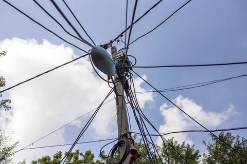 Utility and power cables hang from a pole in the Khilona Wala Bagh slum cluster in New Delhi. (Photographer: Prashanth Vishwanathan/Bloomberg)