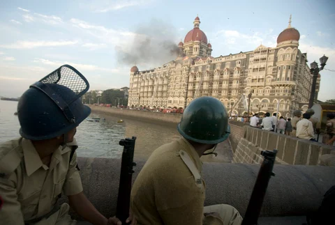 Police personnel watch the Taj Mahal Hotel, set ablaze by terrorists, in Mumbai, India, on November 27, 2008. (Photographer: Prashanth Vishwanathan/Bloomberg)