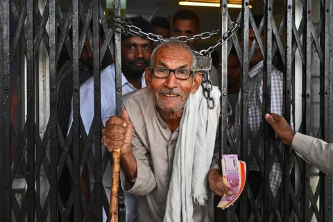 A farmer exits a bank holding a new Indian two thousand rupee banknote. (Photographer: Anindito Mukherjee/Bloomberg)
