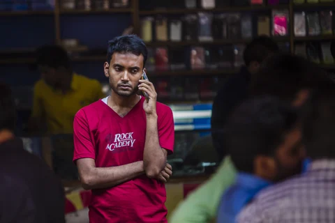 A man speaks on a mobile phone outside a mobile phone store in New Delhi. (Photographer: Prashanth Vishwanathan/Bloomberg)