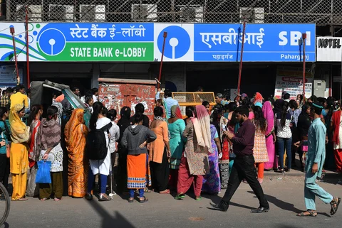 People wait in line outside a State Bank of India (SBI) branch in Delhi (Photographer: Anindito Mukherjee/Bloomberg)