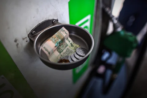 An Indian five rupee note and one rupee coins sit in a money collection tray at a petrol pump in India (Photographer: Dhiraj Singh/Bloomberg)
