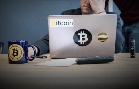 An employee uses a laptop computer branded with bitcoin logos. (Photographer: Christophe Morin/Bloomberg)