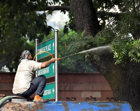 An NDMC worker sprays water on a tree to combat toxic smog and dust, and improve the air quality of the capital. (Image: PTI Photo)