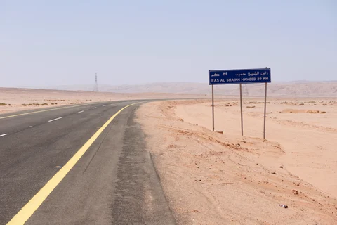 A road sign sits beside a desert highway indicating the distance to the bay at Ras Hameed, where the new mega-city of Neom is planned, Saudi Arabia, on February 26, 2016. (Photographer: Glen Carey/Bloomberg)