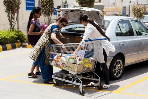Customers load a car with goods from their shopping cart in the parking lot (Photographer: Udit Kulshrestha/Bloomberg)