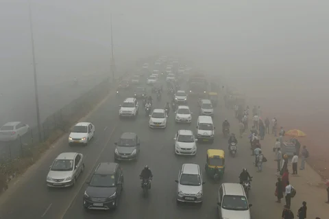 Vehicles plying at a road in smog, in New Delhi on Wednesday morning. (Image: PTI)