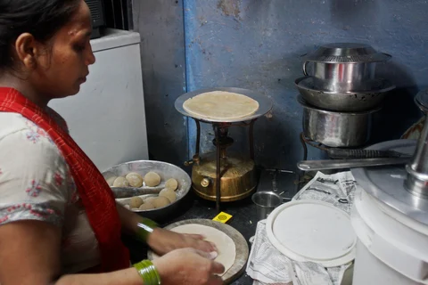 Shabana Khan makes <i>roti</i> for her husband and four children in Mumbai, India. (Photographer: Dhiraj Singh/Bloomberg)