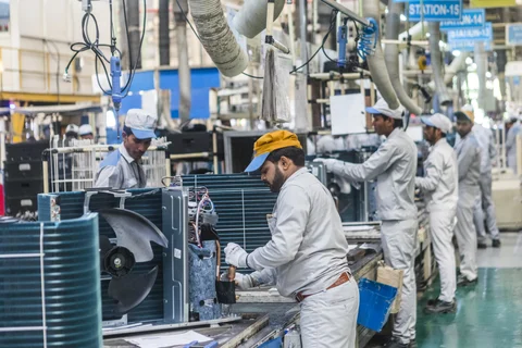 Employees work on the outdoor units of split system air conditioners on an assembly line. (Photographer: Prashanth Vishwanathan/Bloomberg)