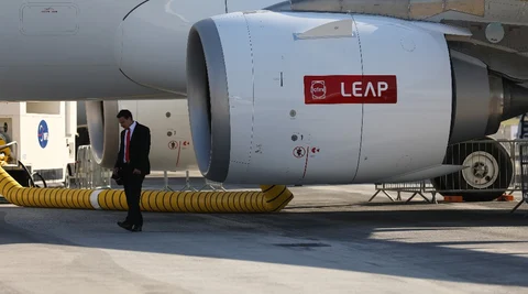 An attendee stands beside a LEAP jet engine, manufactured by CFM International, on an Airbus SE A321 passenger aircraft (Photographer: Chris Ratcliffe/Bloomberg) 