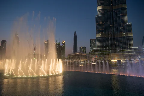 Lights illuminate a water fountain show outside the Dubai Mall at the base of the Burj Khalifa tower, right, in Dubai. (Photographer: Jasper Juinen/Bloomberg)