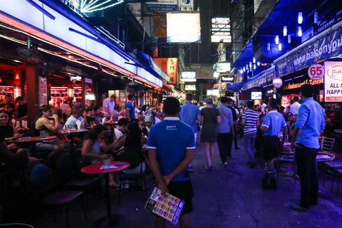 An employee, center, stands between bars at night in the Silom area of Bangkok, Thailand. (Photographer: Dario Pignatelli/Bloomberg)