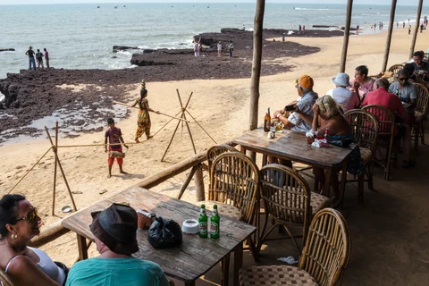 Tourists and visitors sit in a restaurant as children perform at Anjuna beach in Anjuna, Goa. (Photograph: Sanjit Das/Bloomberg)