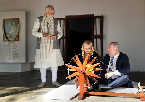 Prime Minister Narendra Modi and Israeli Prime Minister Benjamin Netanyahu assist Sara Netanyahu after she tried a traditional ‘charkha’ or spinning wheel during their visit to Sabarmati Ashram in Ahmedabad. (Image: PTI)