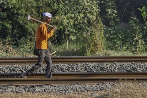 A worker carries a sledgehammer as he walks along rail tracks in Mumbai. (Photographer: Dhiraj Singh/Bloomberg)