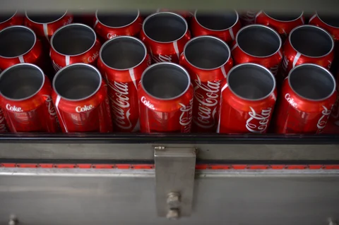 Empty Coca-Cola Classic cans move along a conveyor at a production facility. (Photographer: Carla Gottgens/Bloomberg)