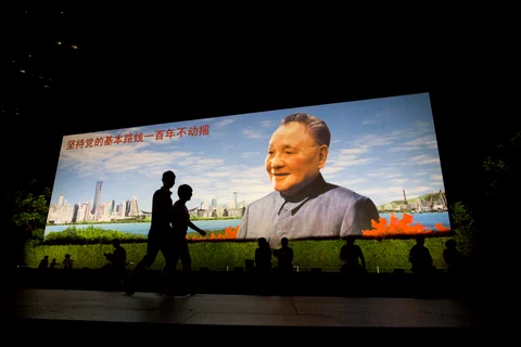 People walk past a portrait of China’s former leader Deng Xiaoping in the Luohu district of Shenzhen, China. (Photographer: Brent Lewin/Bloomberg)