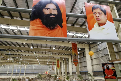 Posters depicting yoga guru Baba Ramdev, top left, and Acharya Balkrishna Ji, chief executive officer of Patanjali Ayurved Ltd., top right, are displayed inside a warehouse operated by the company. (Photographer: Dhiraj Singh/Bloomberg) 