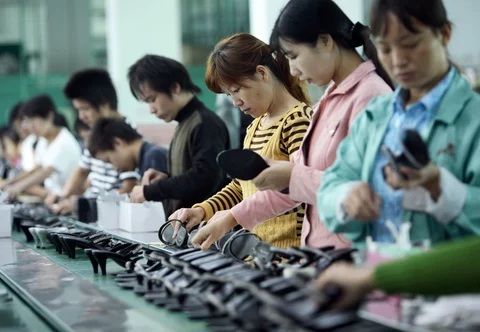 Workers labor on the production line for women’s shoes at the Junsheng Shoe factory in Dongguan, China. (Photographer: Qilai Shen/Bloomberg News)