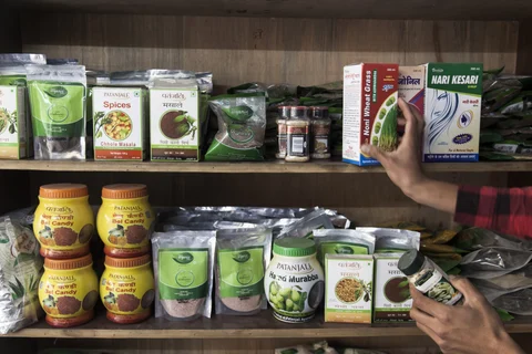 A customer holds a container of pumpkin seeds while picking out a box of wheat grass at a Patanjali Ayurved Ltd. store in New Delhi. (Photographer: Udit Kulshrestha/Bloomberg) 