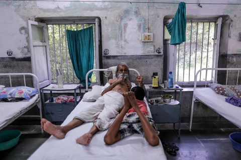 A patient talks with a boy on a bed inside the Indian Railways Divisional Railway Hospital in Mughalsarai, Uttar Pradesh. (Photographer: Dhiraj Singh/Bloomberg)
