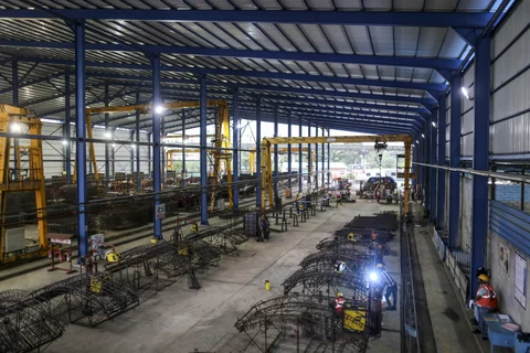 Workers labor on the steel reinforcing frames of precast concrete tunnel segments at the Mumbai Metro Rail Corp. (MMRC) casting yard in Mumbai, India. (Photographer: Dhiraj Singh/Bloomberg)