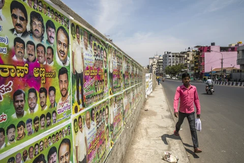 A pedestrian walks past election campaign posters for the Janata Dal (Secular) Party in Bengaluru. (Photographer: Prashanth Vishwanathan/Bloomberg)