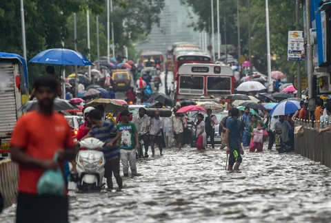 Vehicles and pedestrians wade through a water logged street following heavy monsoon showers in Mumbai. (Source: PTI)