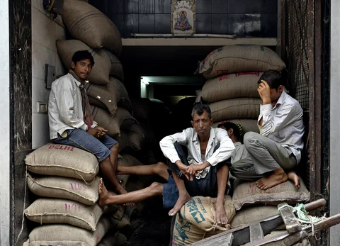 Workers sit on sacks of goods at a wholesale market in the Old Delhi area of Delhi, India, on July 1, 2017. (Photographer: Anindito Mukherjee/Bloomberg)