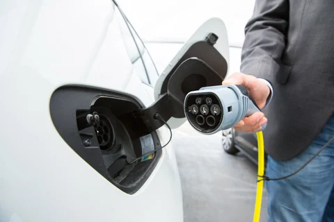 A driver charges a Volkswagen e-Golf electric automobile at a charging station outside the Volkswagen AG factory in Wolfsburg, Germany. (Photographer: Krisztian Bocsi/Bloomberg)