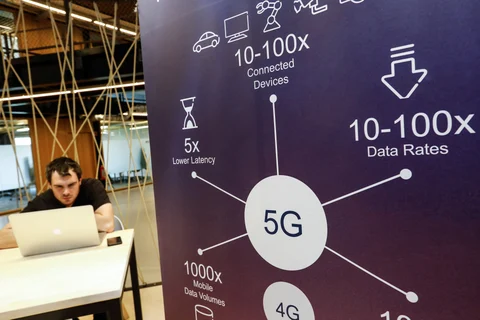 An attendee uses a laptop computer beside a 5G information sign. (Photographer: Dario Pignatelli/Bloomberg)