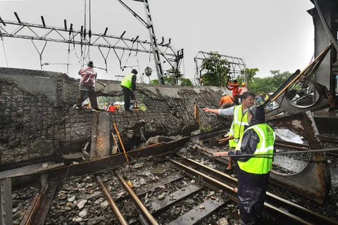Rescue workers clear the debris of Gokhale foot overbridge that collapsed on the Western Railway tracks, at Andheri station following heavy rain, in Mumbai on Tuesday, (Photographer: Shirish Shete/PTI)
