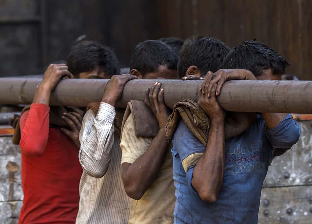 Workers carry an iron pipe on their shoulders at a steel and iron market area in India. (Photographer: Prashanth Vishwanathan/Bloomberg)