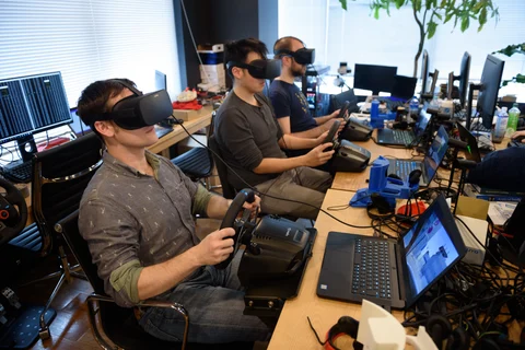 Employees wearing virtual reality headsets use Sony PlayStation wheel controllers to perform maneuvers on virtual simulations in Tokyo, Japan, on March 16, 2018. (Photographer: Akio Kon/Bloomberg)