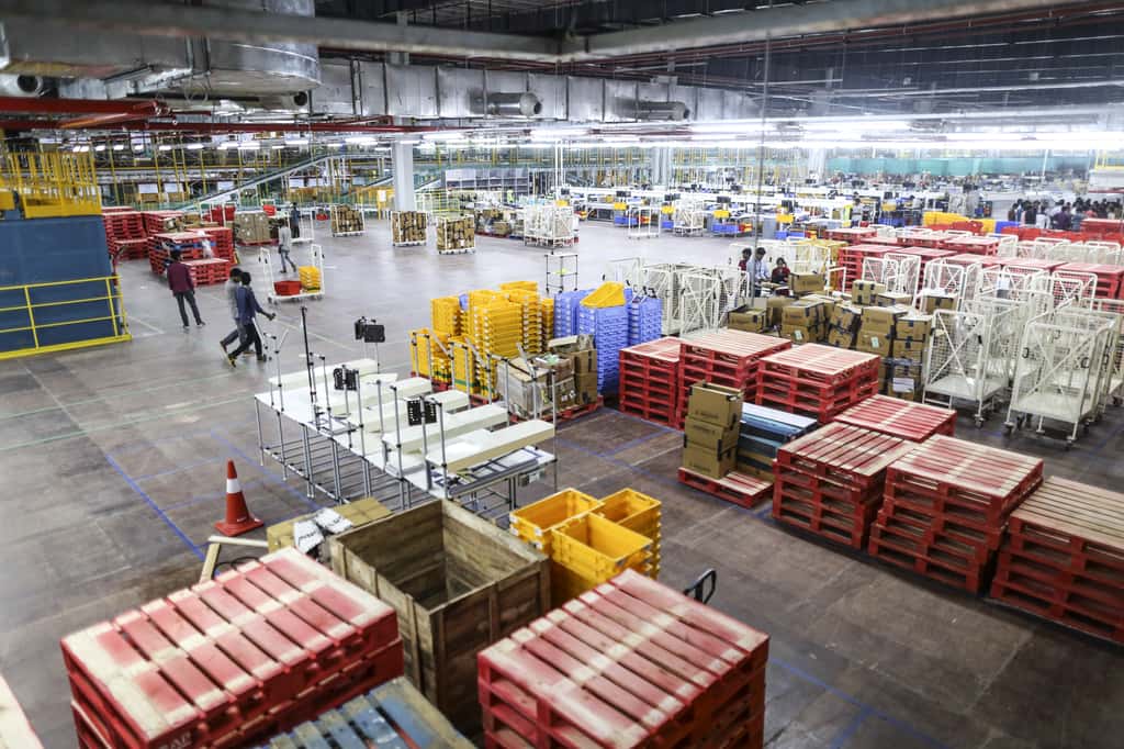 Employees walk past stacked palettes in the warehouse at the Amazon.com Inc. fulfillment center in Hyderabad, India. (Photographer: Dhiraj Singh/Bloomberg)