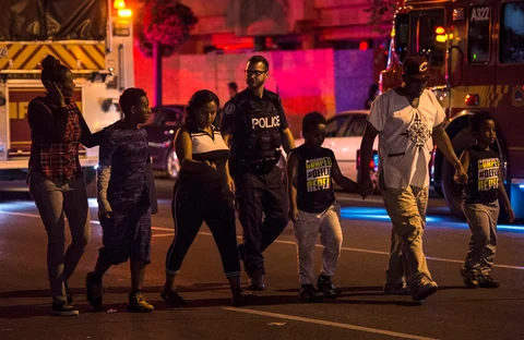 Police escort civilians away from the scene of a shooting, Sunday. (Source: PTI)