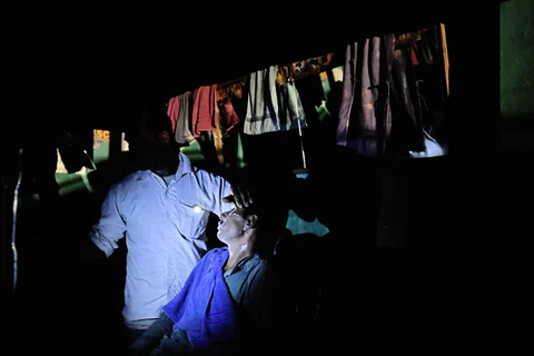 A barber shop illuminated by the torch function of a mobile phone, on the outskirts of Alwar, Rajasthan, on April 17, 2018. (Photographer: Anindito Mukherjee/Bloomberg)