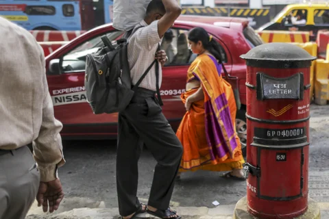 Pedestrians walk past an India Post mail box outside the postal operator’s head office in Mumbai. (Photographer: Dhiraj Singh/Bloomberg)