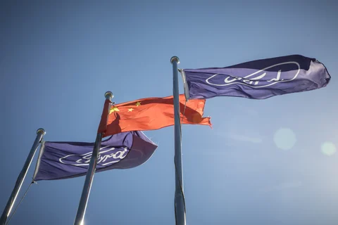 A Chinese flag, center, and the Ford Motor Co. corporate flags are flown at a Ford dealership in Shanghai, China, on July 19, 2018. (Photographer: Qilai Shen/Bloomberg)