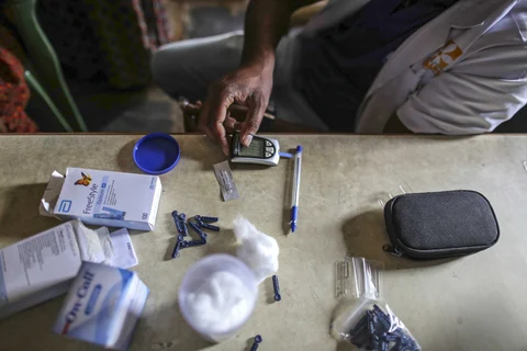 A medical team uses a glucometer to check the blood glucose level of a patient at a mobile clinic in Pancharala, on the outskirts of Bengaluru, India. (Photographer: Dhiraj Singh/Bloomberg)