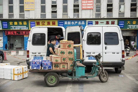 Men load boxes of fruit into the back of a van at a wholesale market in Shanghai, China, on July 13, 2018. (Photographer: Qilai Shen/Bloomberg)